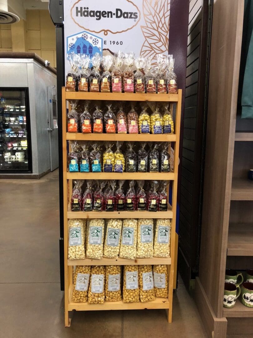 A display rack of assorted häagen-dazs ice cream products in a store, featuring neatly arranged jars and boxes on wooden shelves.